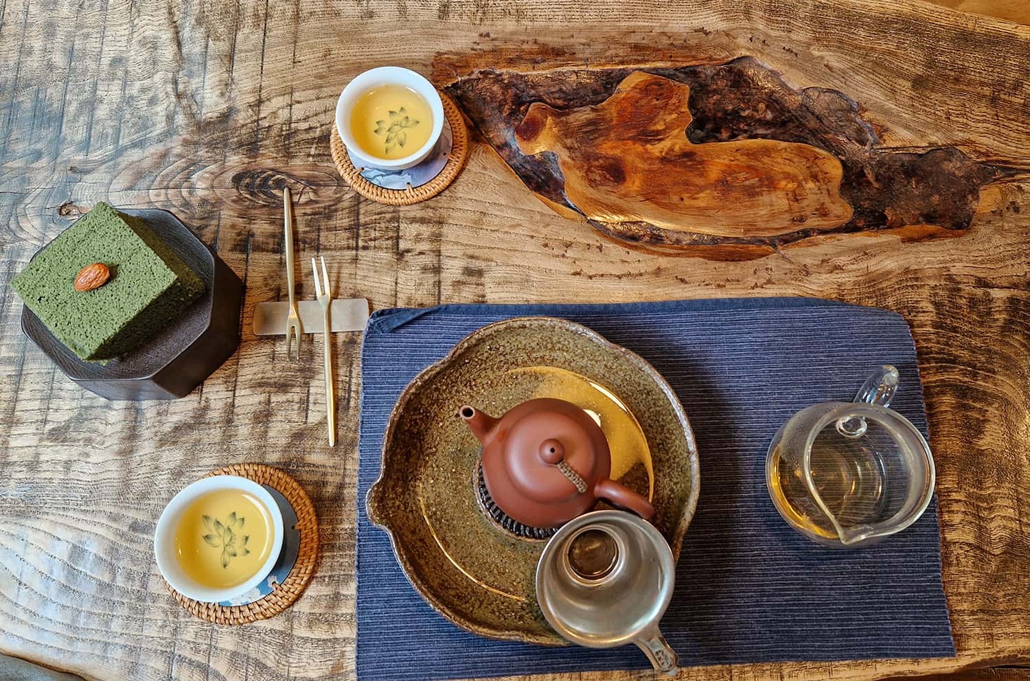 traditional Korean tea pot, cups and mugwort sponge cake on a wooden table seen from above