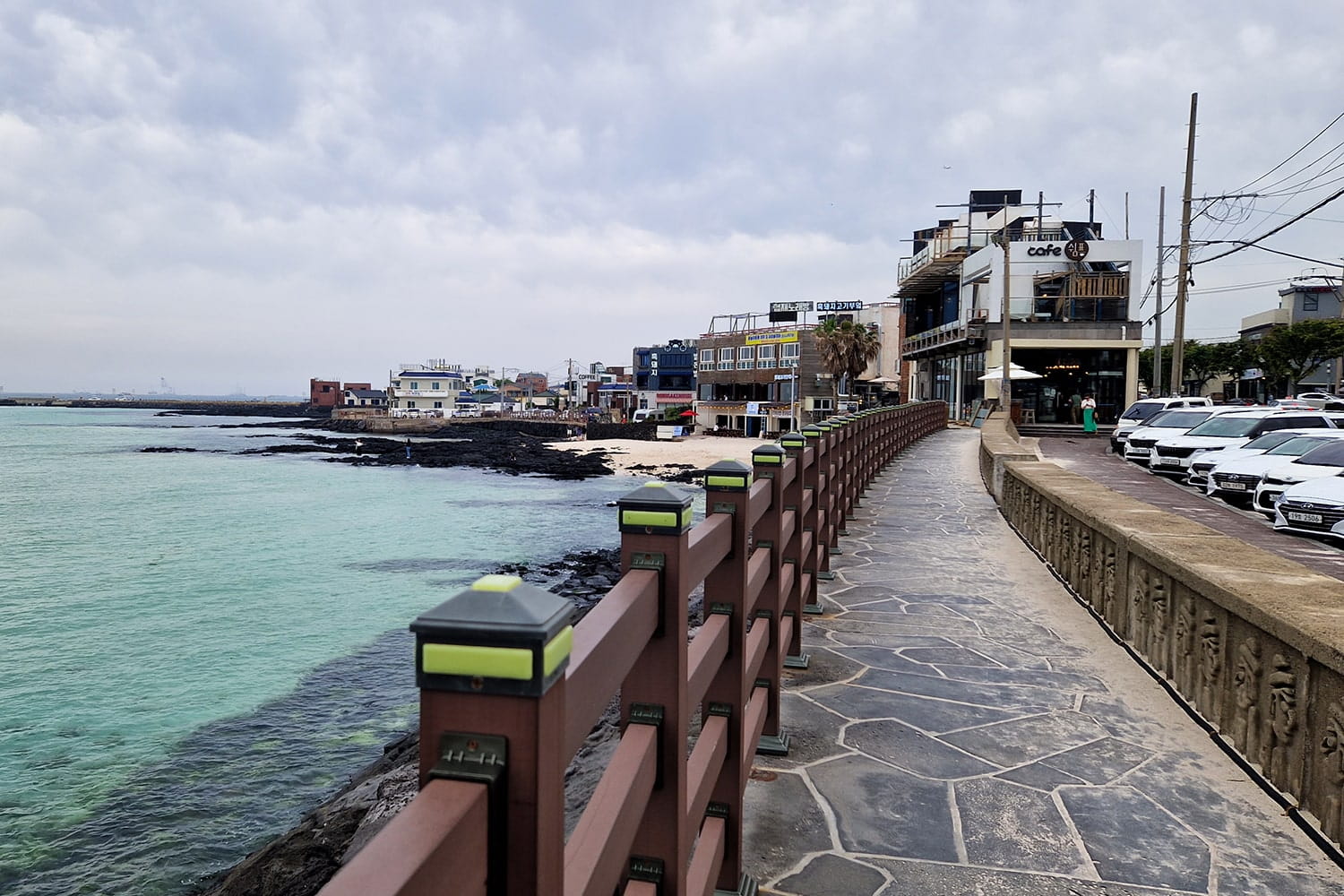 walkway alongside the sea on the left and parking on the right on Jeju island