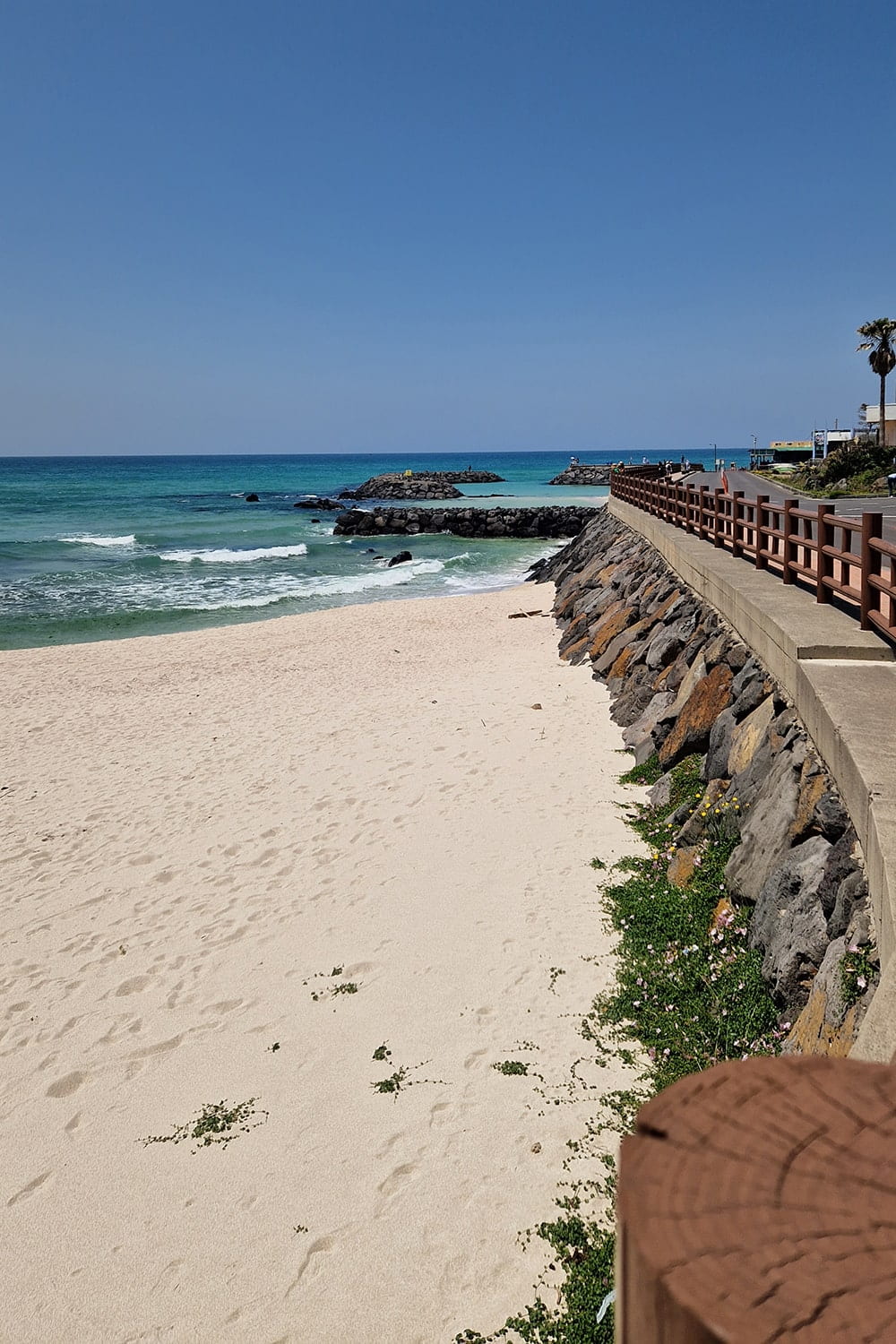 Jeju island coastal road with white sand beach on the left and sea in the background