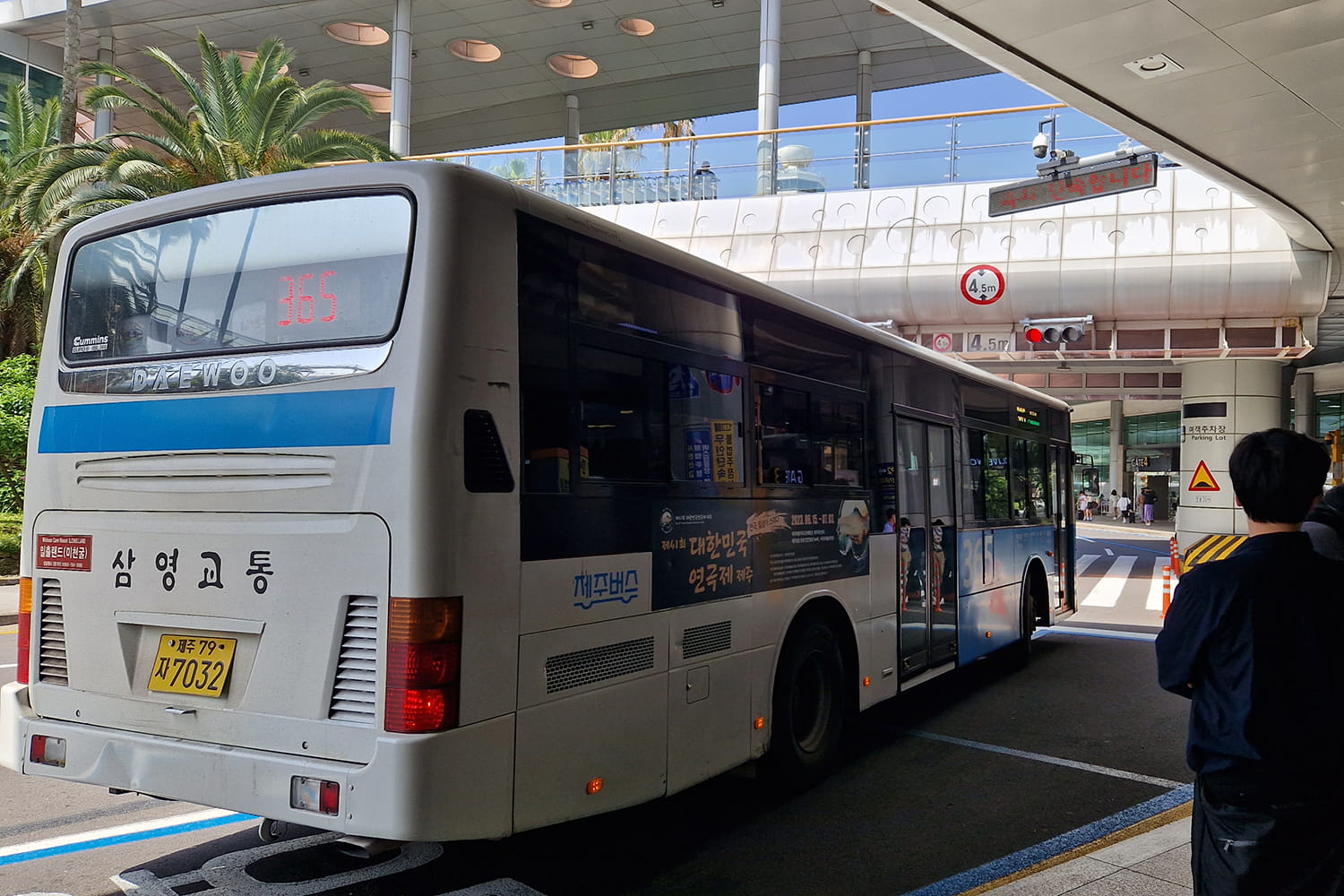 Bus standing in front of Jeju Airport and people waiting in line to the right