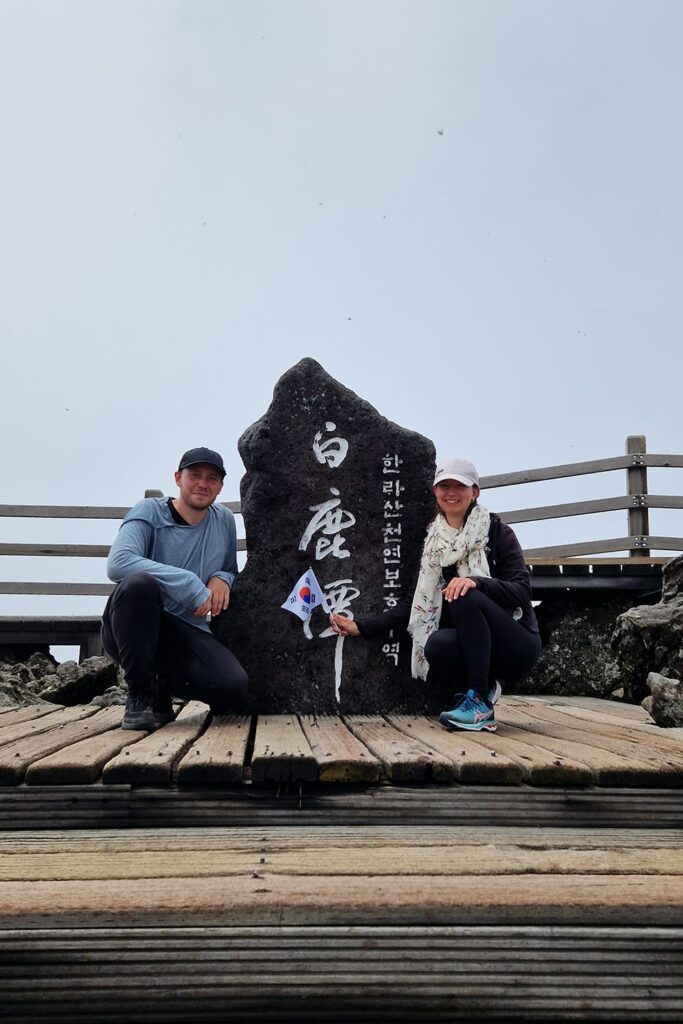 couple sitting in front of Mt. Hallasan summit stone mark
