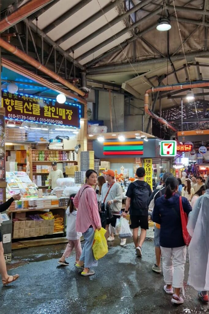 people walking past stalls in dongmun food market in jeju city