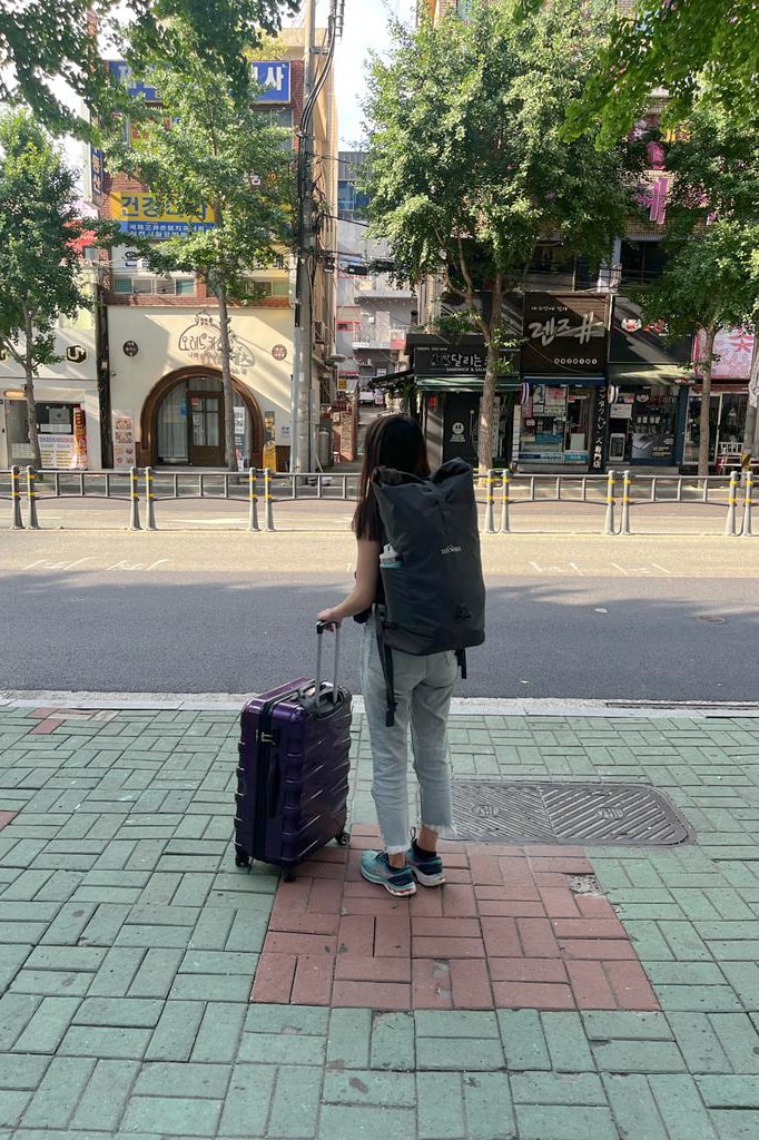 Woman with a suitcase waiting for the bus to arrive.