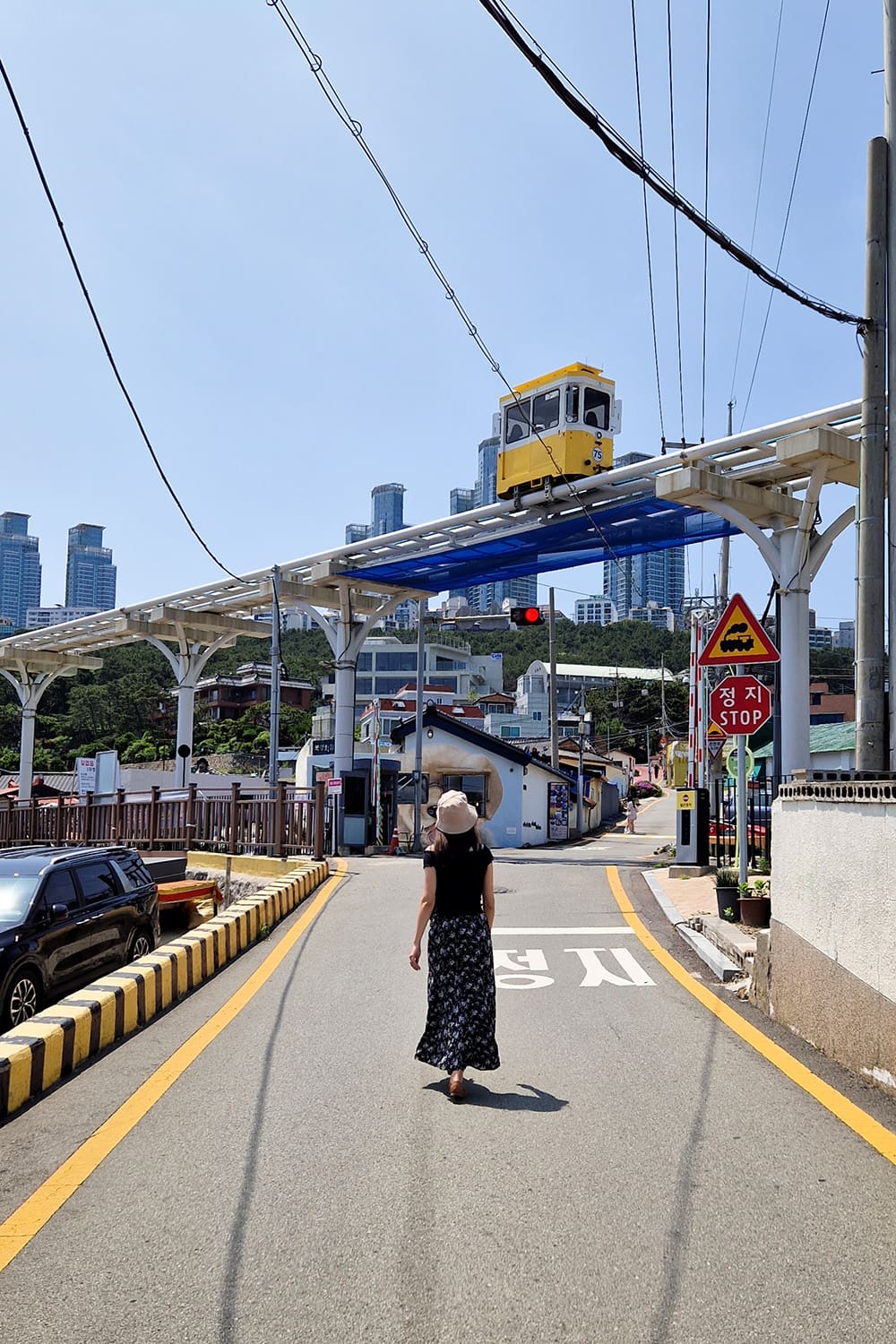 Streetview of a girl walking with the busan sky capsules above her.