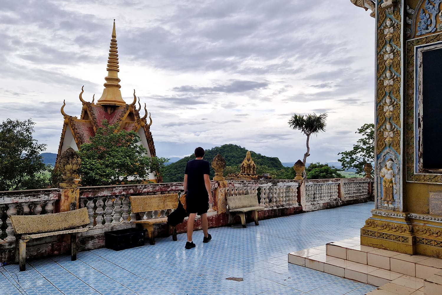 A big temple with a red roof and golden ornaments on a hill overlooking Battambang in Cambodia.