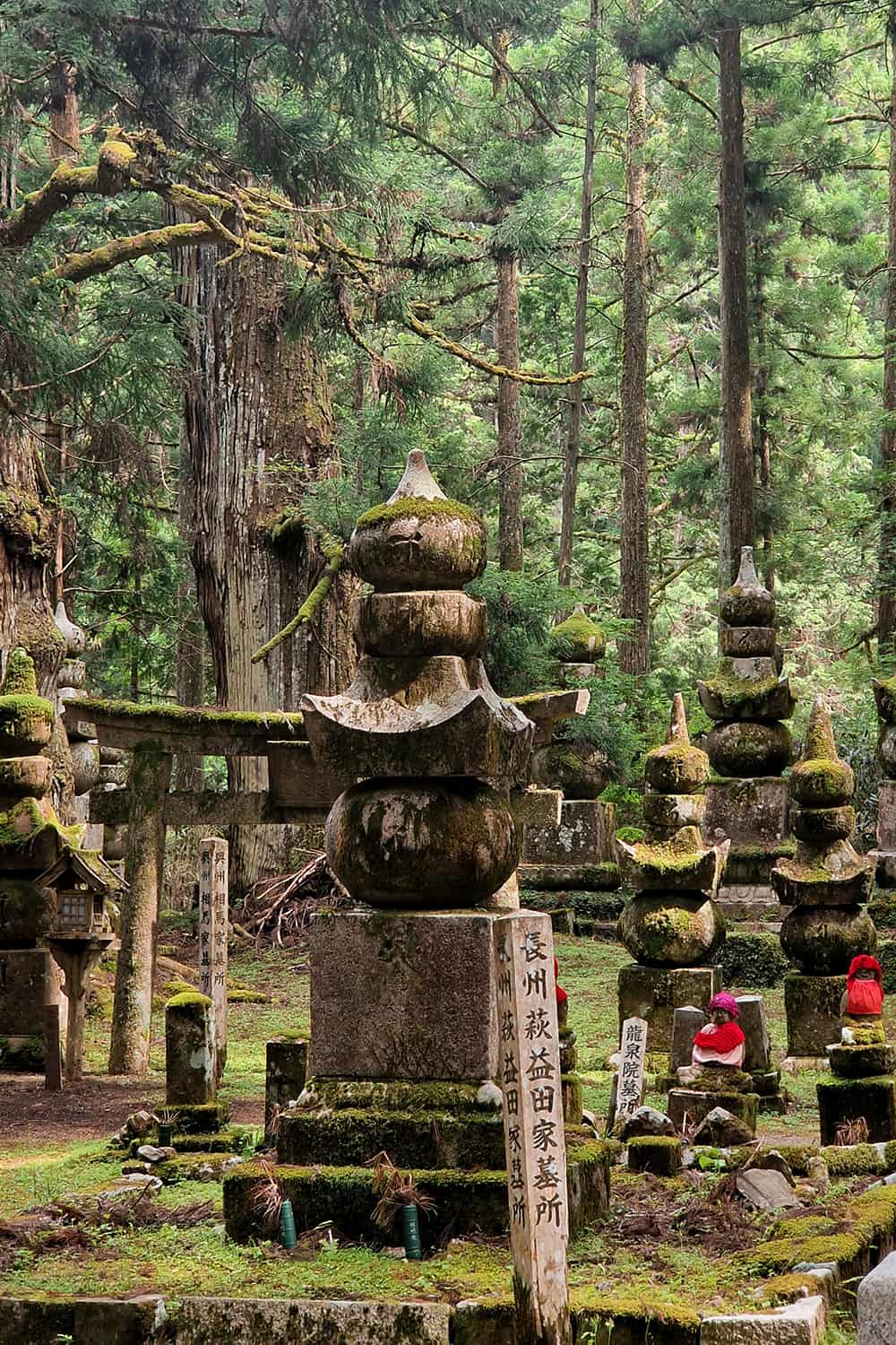 A japanese tombstone with small statues surrounding it.