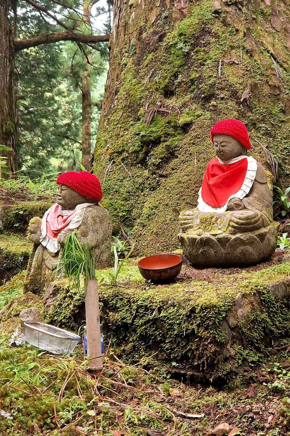 small stone statues put on graves wearing red bonnets.