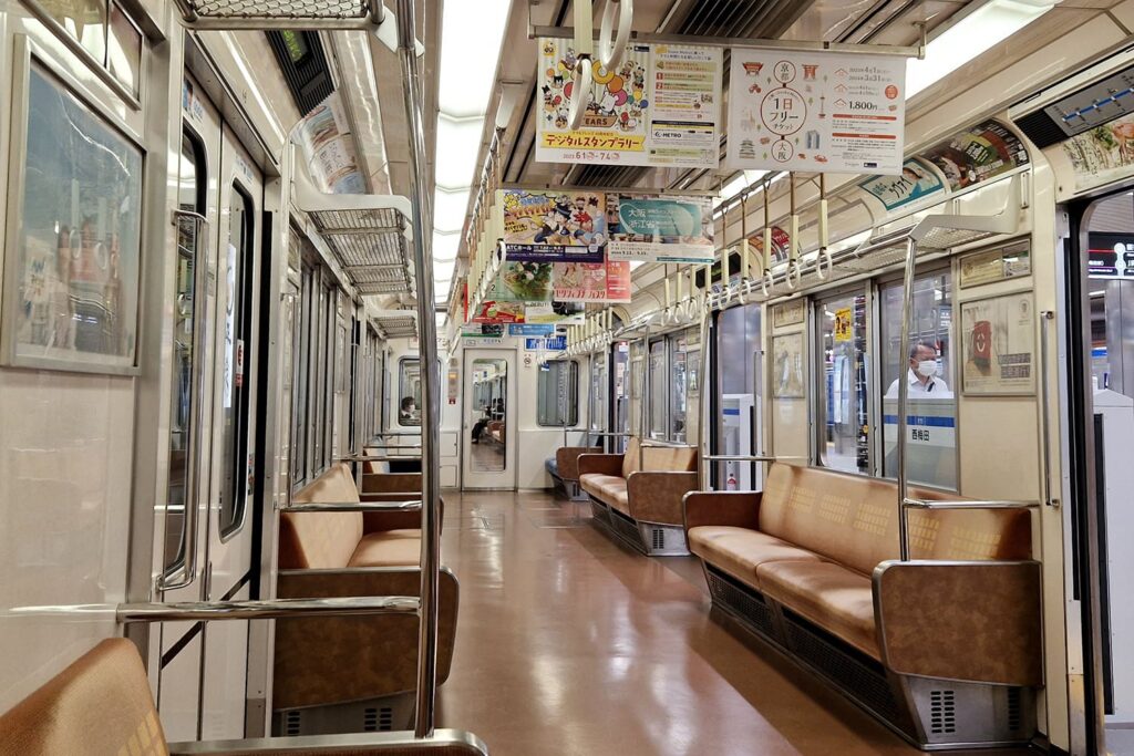 The interior of a local train in Japan, with brown seating benches on both sides.