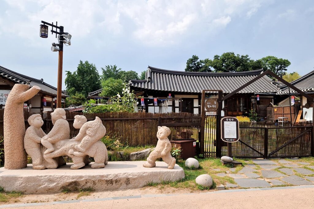 A cafe inside a Hanok Style House with a statue of kids playing in front of it.