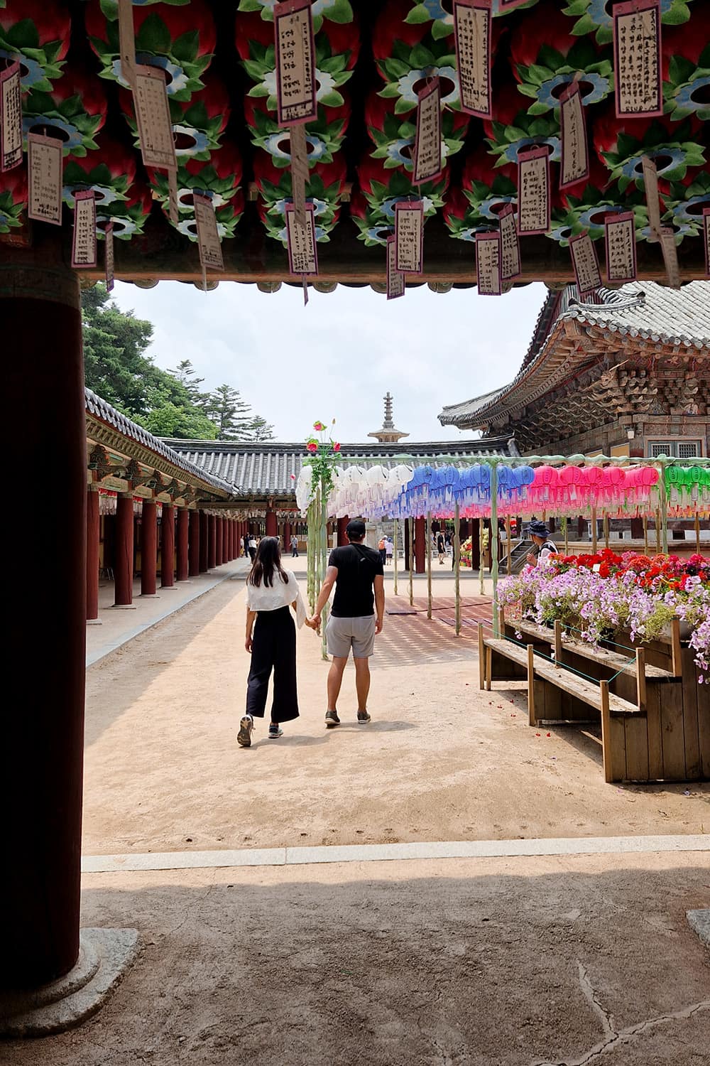 A couple walking through a buddhist temple decorated with lanterns.