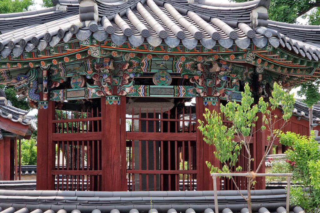 A red south-korean shrine with beautiful green ornaments on the roofs edge.