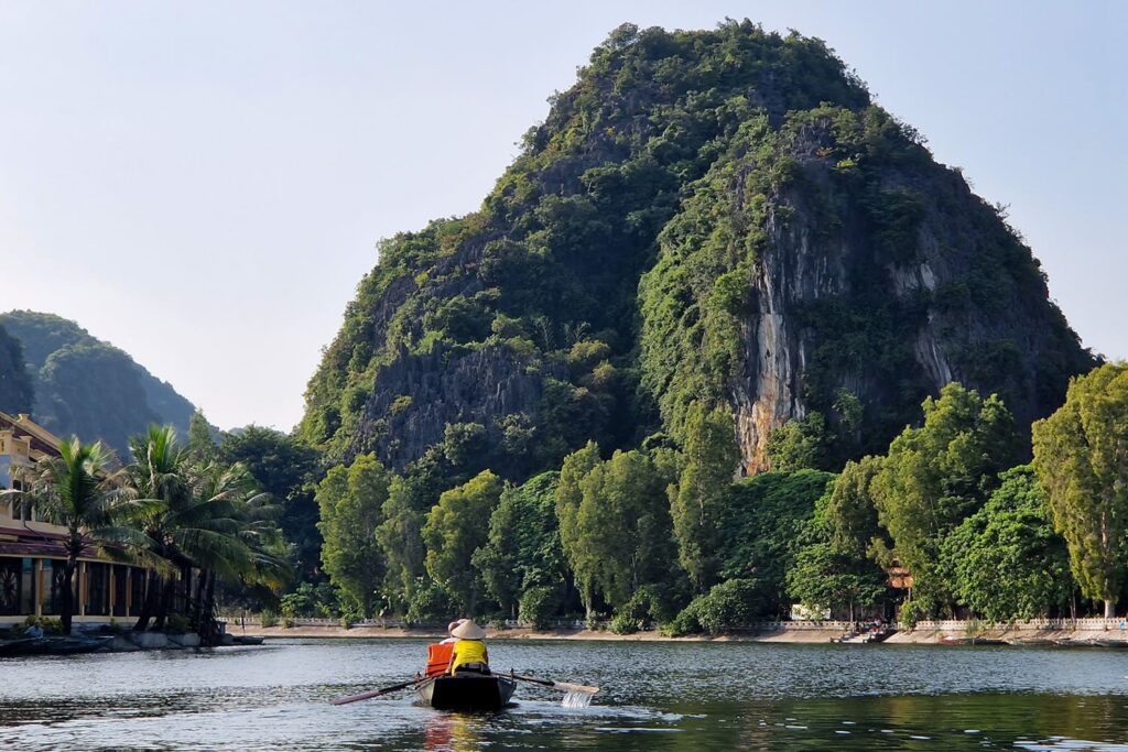 Boats in a river in Ninh Binh with stunning oval formed mountains in the background.