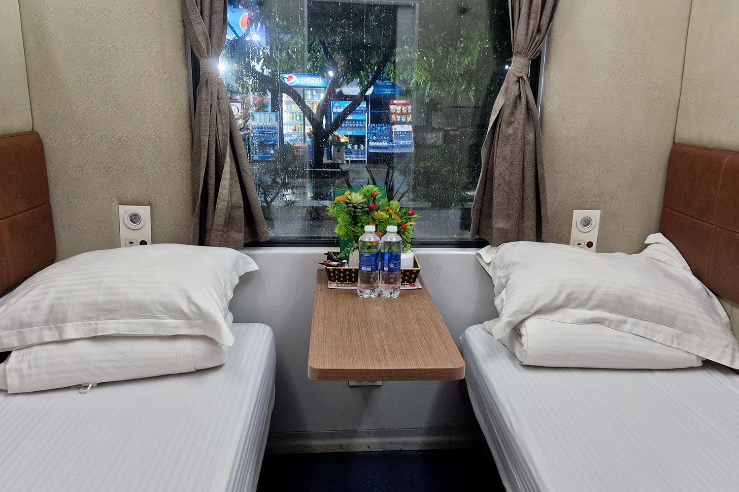 Interior of a sleeper train in Vietnam with two beds and a small table in between.