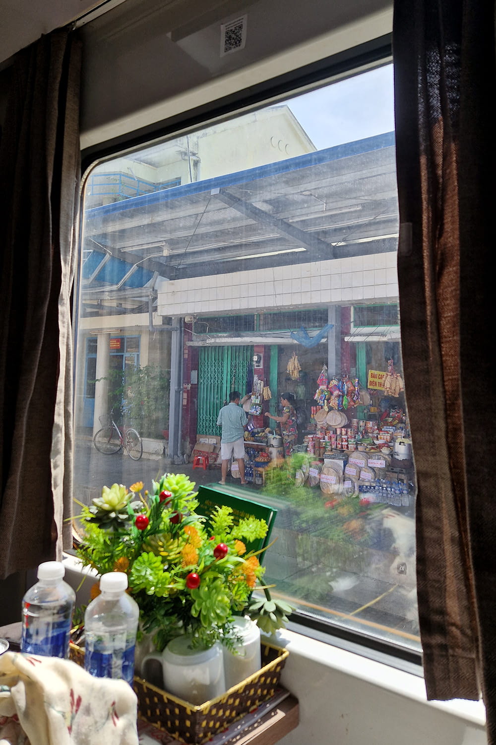 View onto a vendor sellling things while driving past in a sleeper train.