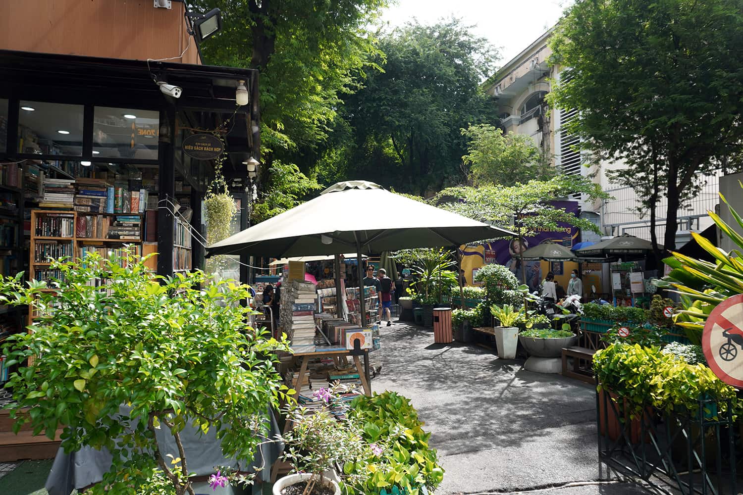 Beautiful entrance to the book street in cho chi minh city, with a lot of plants and outside seating areas.