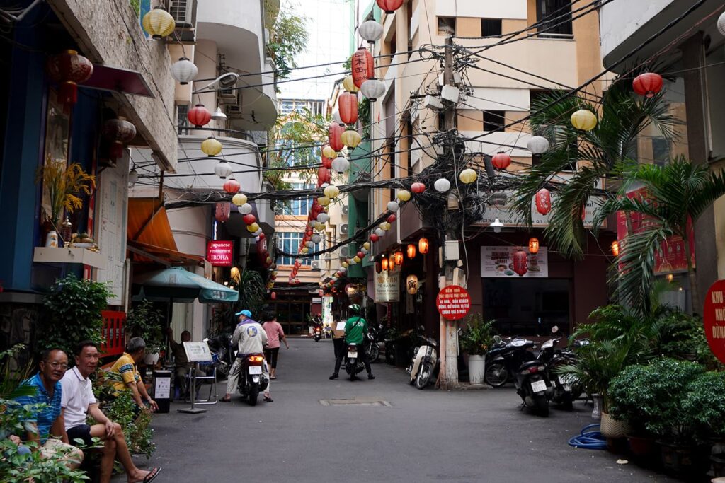 Random street in ho chi minh decorated with different color lanterns and a lot of plants.