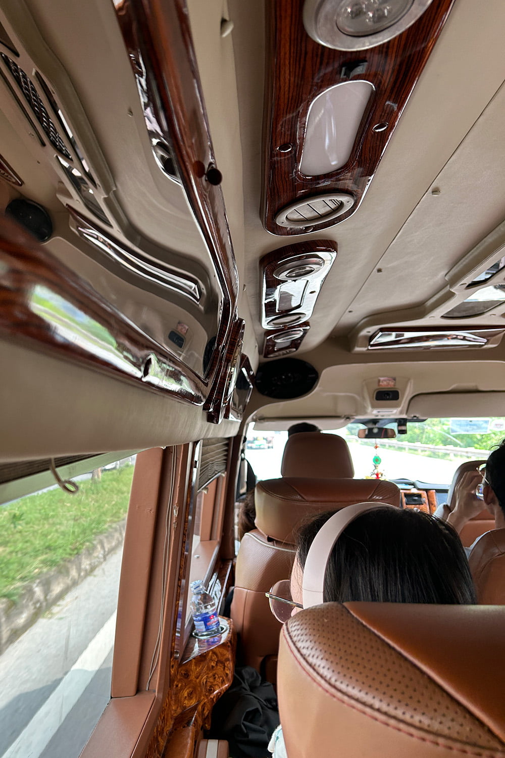 Inside of a more luxurious small travel bus in vietnam with leather seats and beige-brown interior.