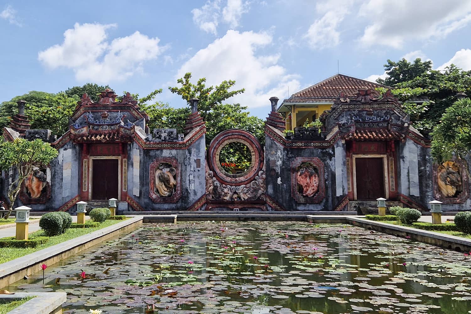 A temple gate with a small pond full of lotus flowers.
