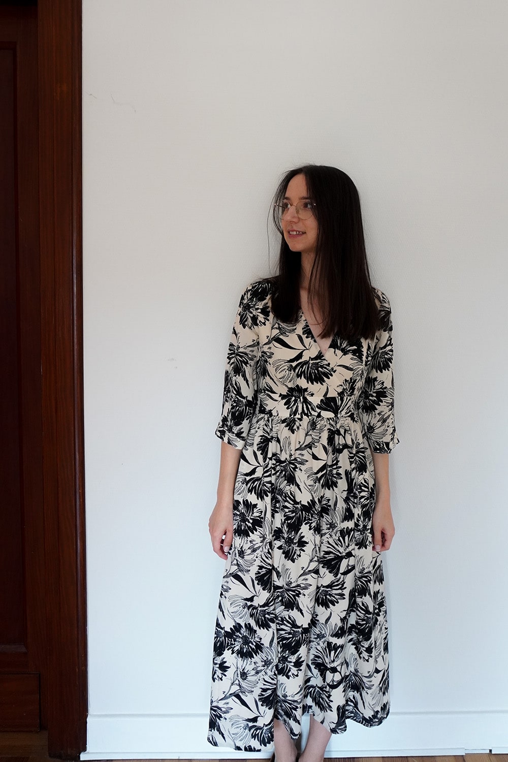 A woman wearing a white with custom made dress with black flower depictions.