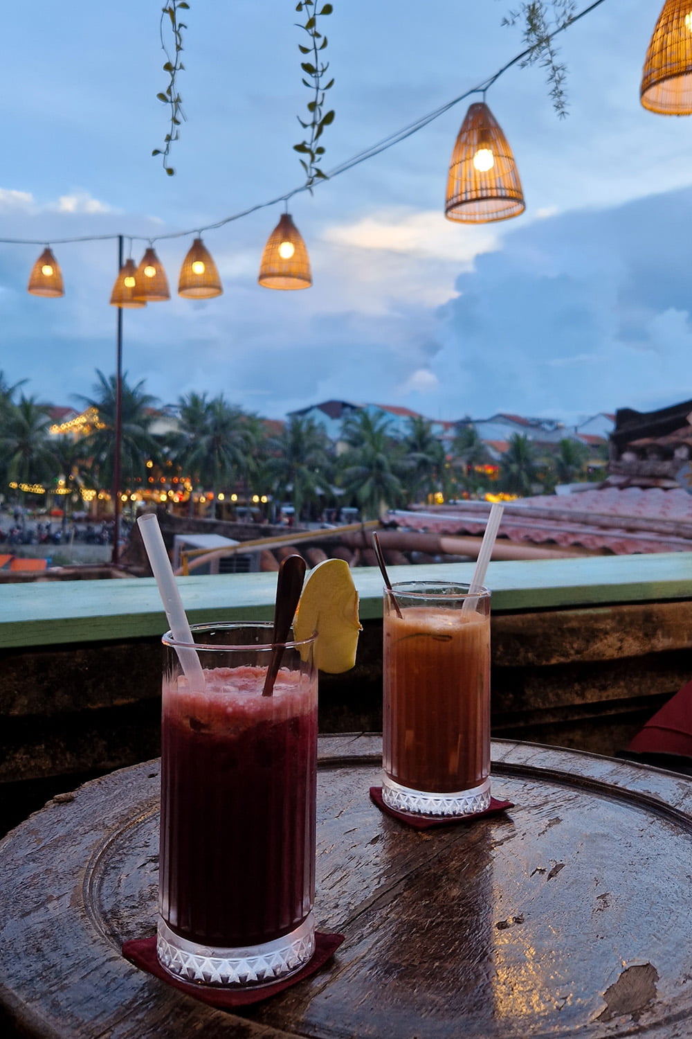 A small rooftop bar in Hoi An with two drinks on the table overlooking the river.